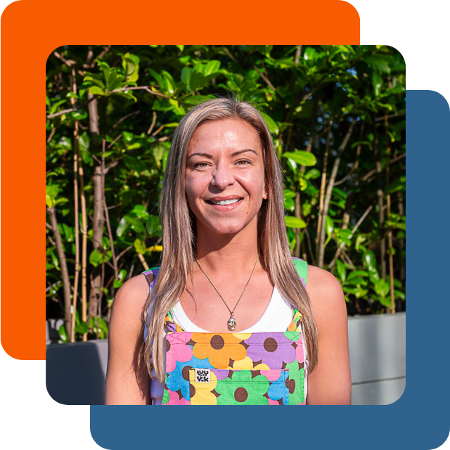 Katie is a young white woman with straight blonde hair. She's pictured here smiling wearing multi-coloured floral dungarees.