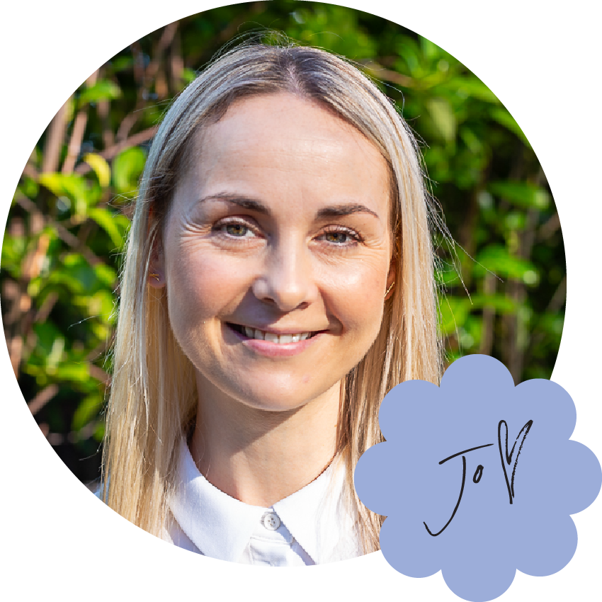 Jo is a middle-aged white woman with long and straight blonde hair. She's pictured here smiling and wearing a white blouse. Her name is handwritten in the corner with thin letters, featuring a tall swooping J with a tiny O tucked underneath its arm, and a big love heart.